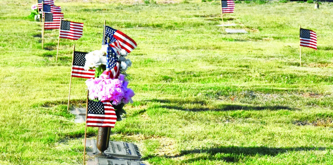 SILENT TRIBUTE--Flags fluttering in local cemeteries this weekend mark a show of respect for those who gave a last full measure of devotion for their country. Take a moment to walk among them and remember. (Photo by Jim Steiert)