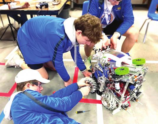 (left to right) Tell Bagley, Luke Schulte and Tanner Birkenfeld, members of Team 16617, Nazareth Robotics, adjust the axle on their robot. Photo by Chloe Birkenfeld.
