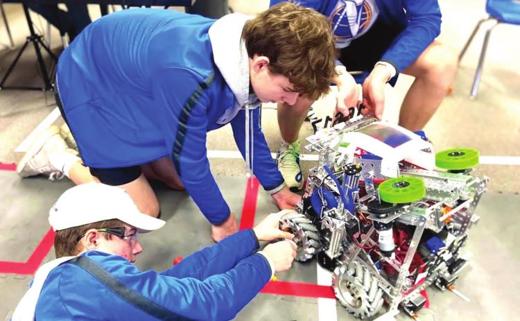 (left to right) Tell Bagley, Luke Schulte and Tanner Birkenfeld, members of Team 16617, Nazareth Robotics, adjust the axle on their robot. Photo by Chloe Birkenfeld.