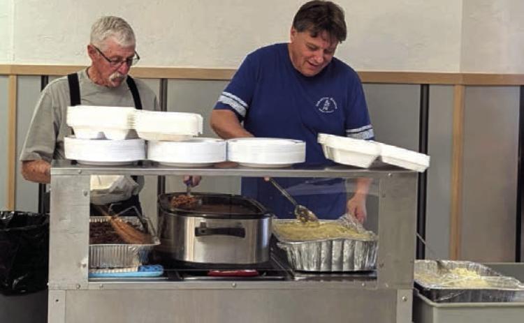 SERVING CHOW—Larry Carlson and Jim Layman serve up food at the Samaritan Hospice Dessert Auction and Brisket Dinner held November 25 at the Kings Manor Lamar Room.