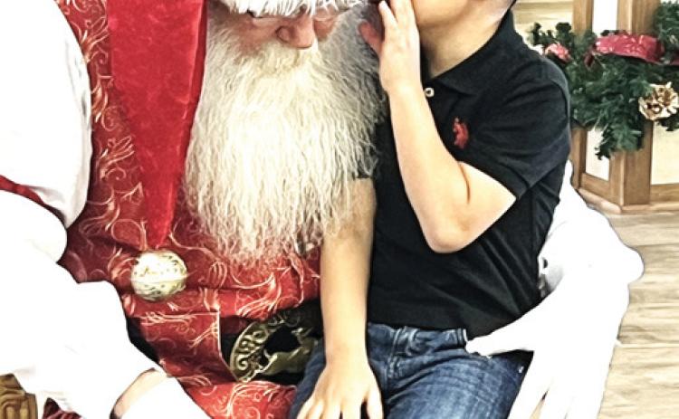 Hart Elementary student Messiah Minjarez whispers to Santa what he wasn’t for Christmas at the Happy State Bank of Hart annual Christmas event. Each year Hart students make a visit to Santa at the local bank.
