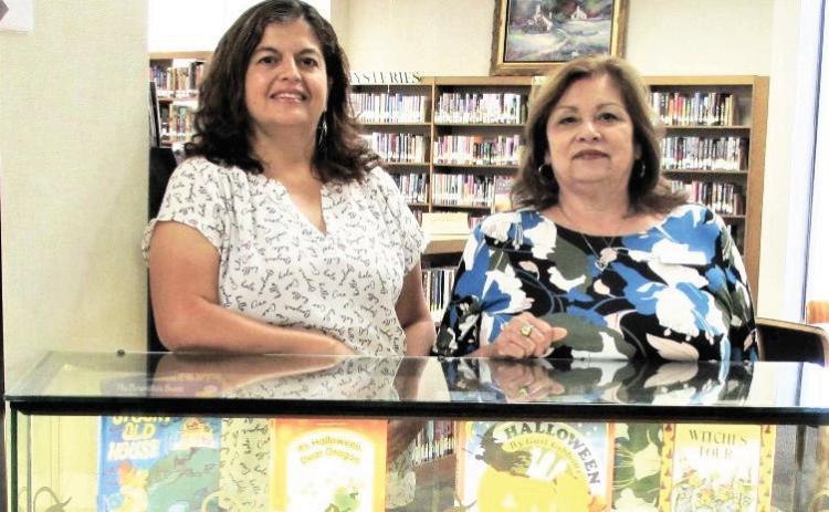 Library display for October 2024 showcases library staff Sulema Oltivero and Patty Padilla and a space for Simon Skeleton to read Halloween stories