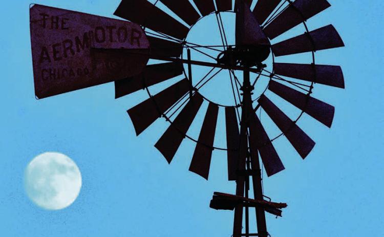 MOONING THE WINDMILL-- Maybe Mother Nature was having a little fun situating the almost-full October harvest moon like it was looking to hitch a ride on the tail of the spinning fan of a classic Aermotor windmill near Dawn Sunday evening, October 5, or maybe the moon was just showing off its natural features to the clanking tower-- bringer of underground rain to the Plains. (Photo by Jim Steiert)