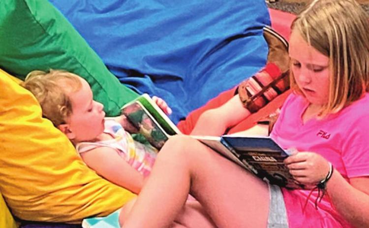 Mackenzie and Ivy Brown reading books at Rhoads Memorial Library during the Summer Reading Program.