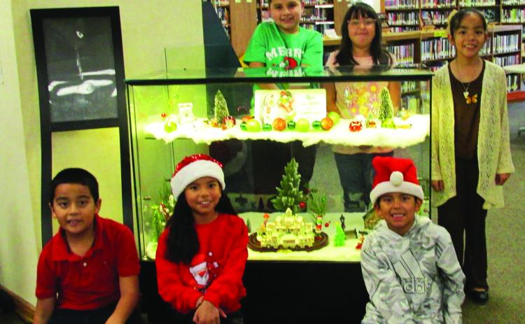 Display for the month of December, 2025, at Rhoads Memorial Library focuses on the Grinch. Family members of the library staff who are showing off the display are, kneeling from left, Francisco Medina, Ava Oltivero, and Andre Oltivero. Standing, from left, are Hugo Sanchez, Kehlani Oltivero, and Grace Medina.