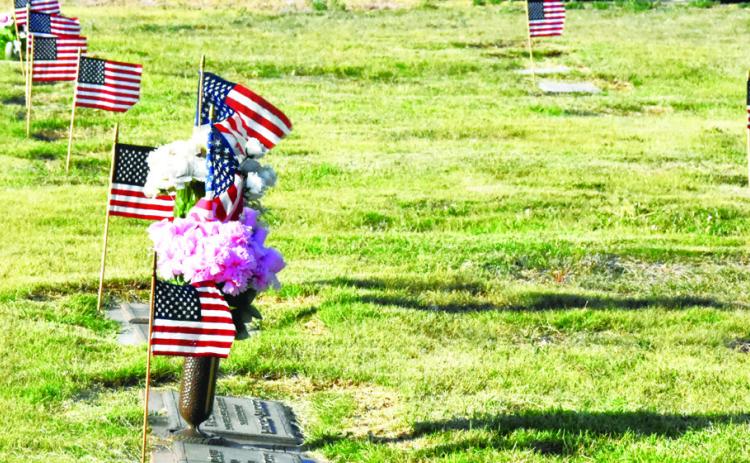 SILENT TRIBUTE--Flags fluttering in local cemeteries this weekend mark a show of respect for those who gave a last full measure of devotion for their country. Take a moment to walk among them and remember. (Photo by Jim Steiert)